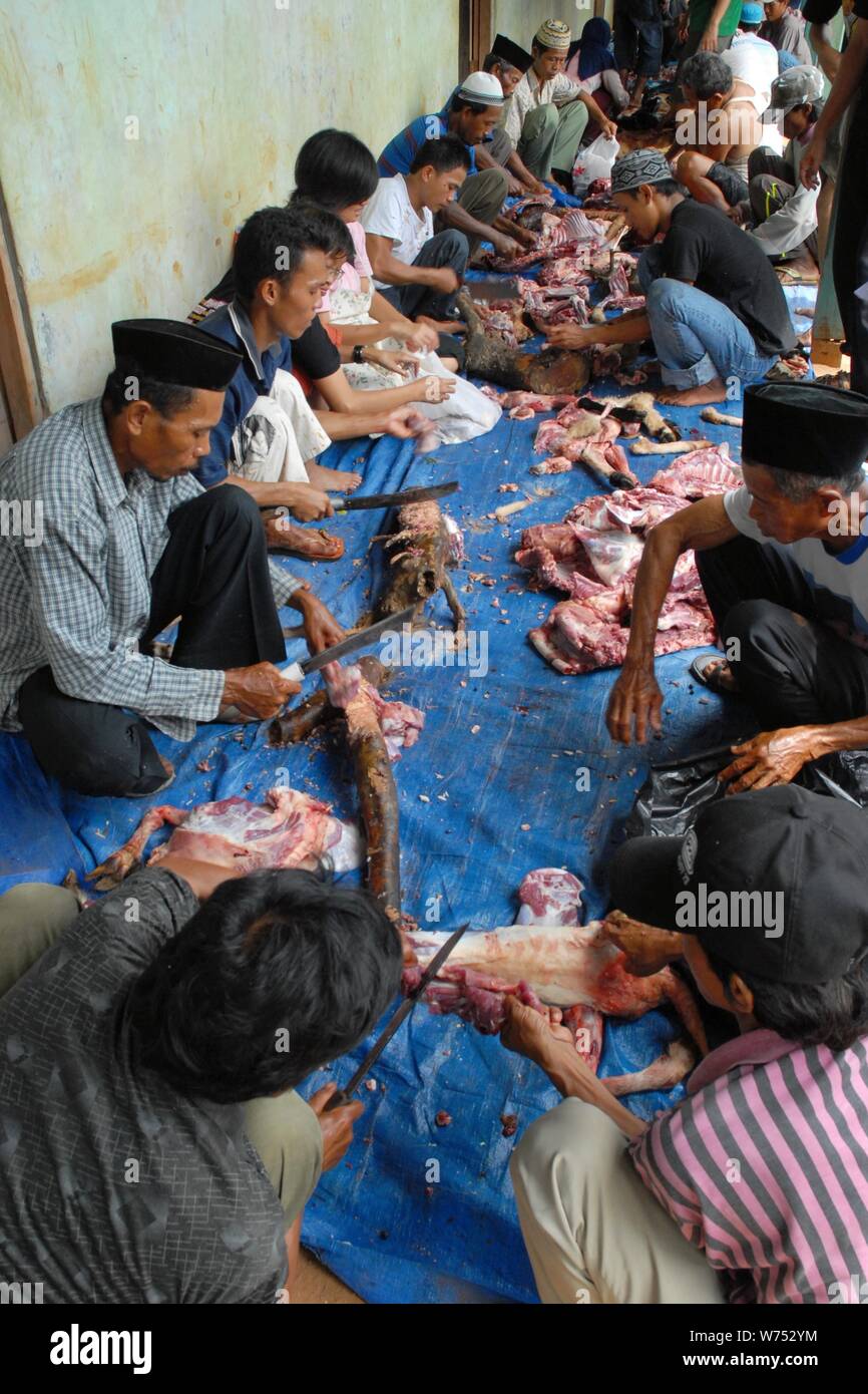 Bogor, West Java, Indonesia - Agosto 2019 : Alcuni lavoratori volontari tagliare e tritare l'agnello sacrificale carne in un paese sottosviluppato. Foto Stock