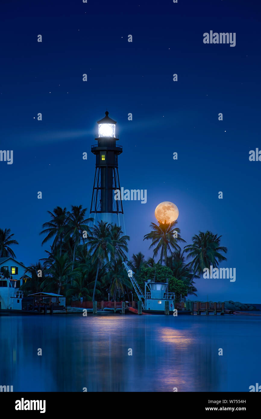 Una bella luna piena sorge a Hillsboro faro di ingresso nella Florida del Sud. Si tratta di un edificio storico ed è stato acceso per la prima volta nel 1907. Foto Stock