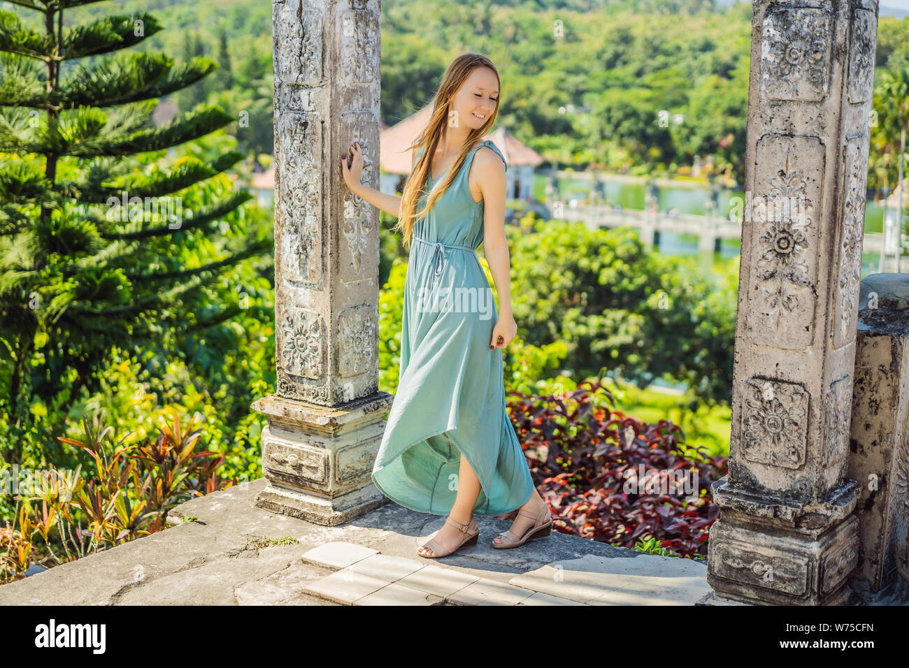 Giovane donna nel vestire in acqua Palace Soekasada Taman Ujung rovine sulla isola di Bali in Indonesia. Incredibile architettura antica. Viaggi e vacanze sfondo Foto Stock