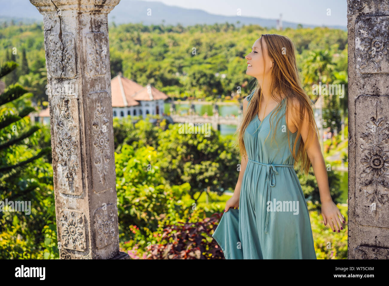 Giovane donna nel vestire in acqua Palace Soekasada Taman Ujung rovine sulla isola di Bali in Indonesia. Incredibile architettura antica. Viaggi e vacanze sfondo Foto Stock