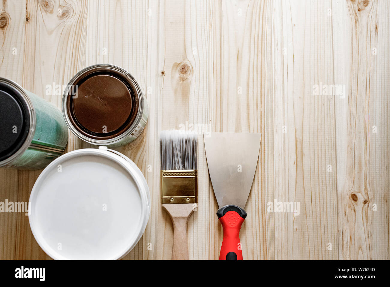 Concetto di riparazione e costruzione domestica. Spatola, Pasta di mastice, pennello, su sfondo testurizzato. Spatola in metallo con manico in plastica e spazzole per vernice. Foto Stock