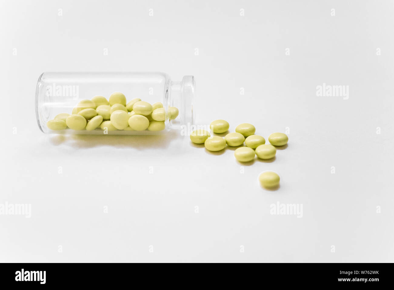 Pillole di colore giallo su sfondo bianco. Giallo medical pillole e compresse di fuoriuscita di un flacone di farmaco. Copia dello spazio. Foto Stock