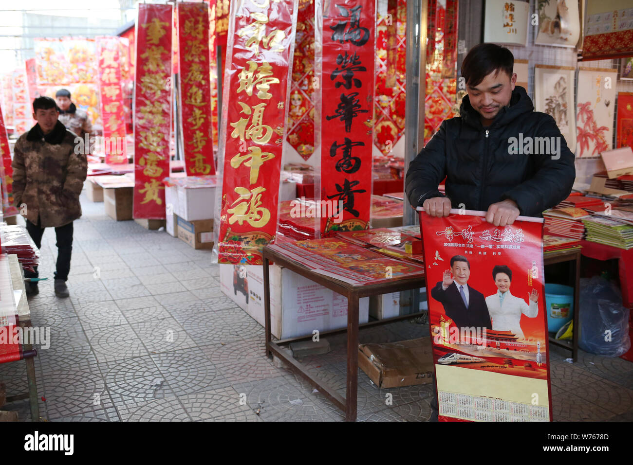 Un proprietario di un negozio di visualizza un calendario rosso sul tema della cinghia "e" la strada con una foto del Presidente cinese Xi Jinping e sua moglie Peng Liyuan per l'unità di protezione e commutazione Foto Stock