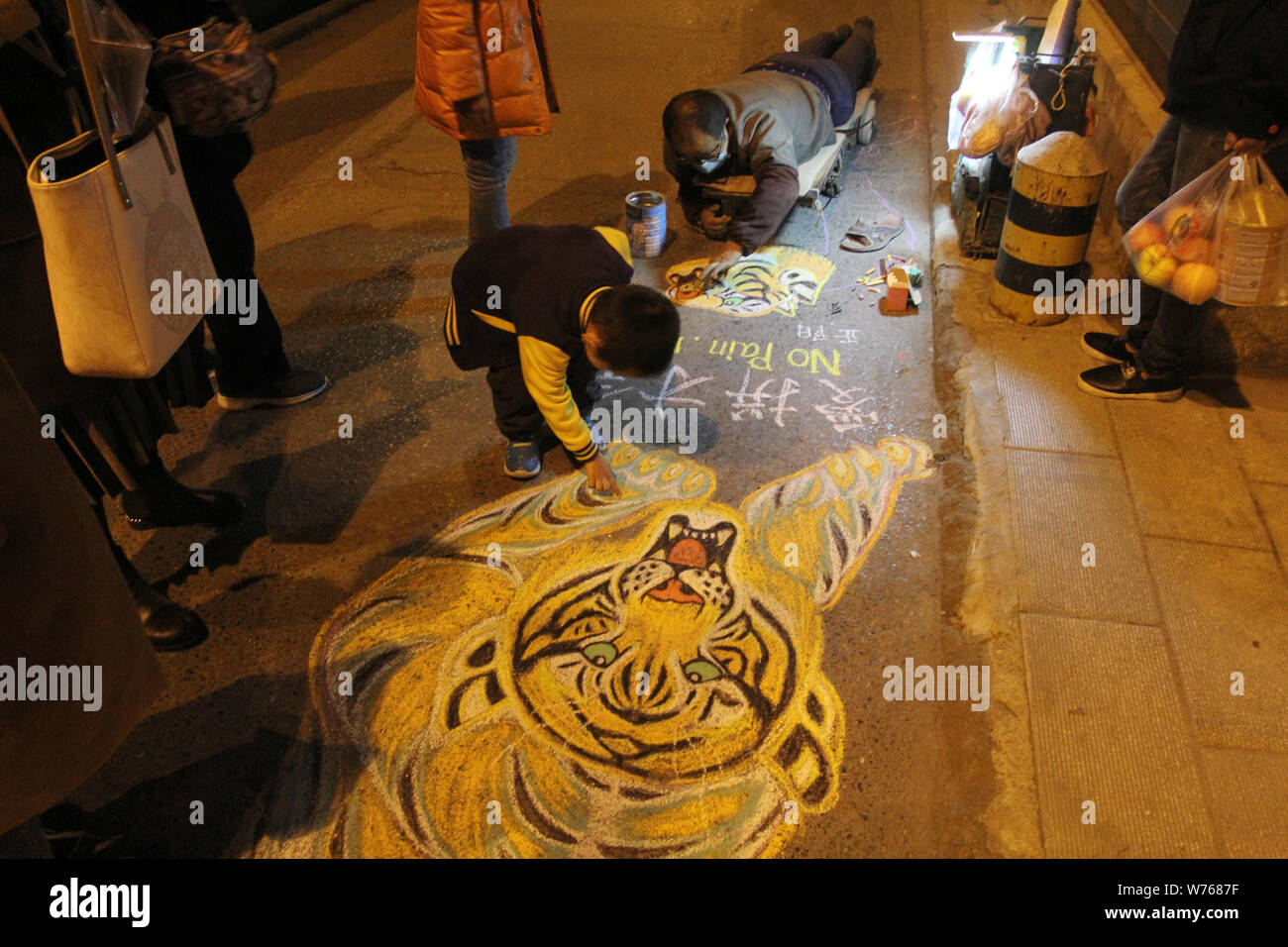 Pedoni cinesi stop per donare denaro come un disabile uomo cinese è il disegno di un live-come tiger su un marciapiede in città di Wuhan, Cina centrale di Hubei pro Foto Stock