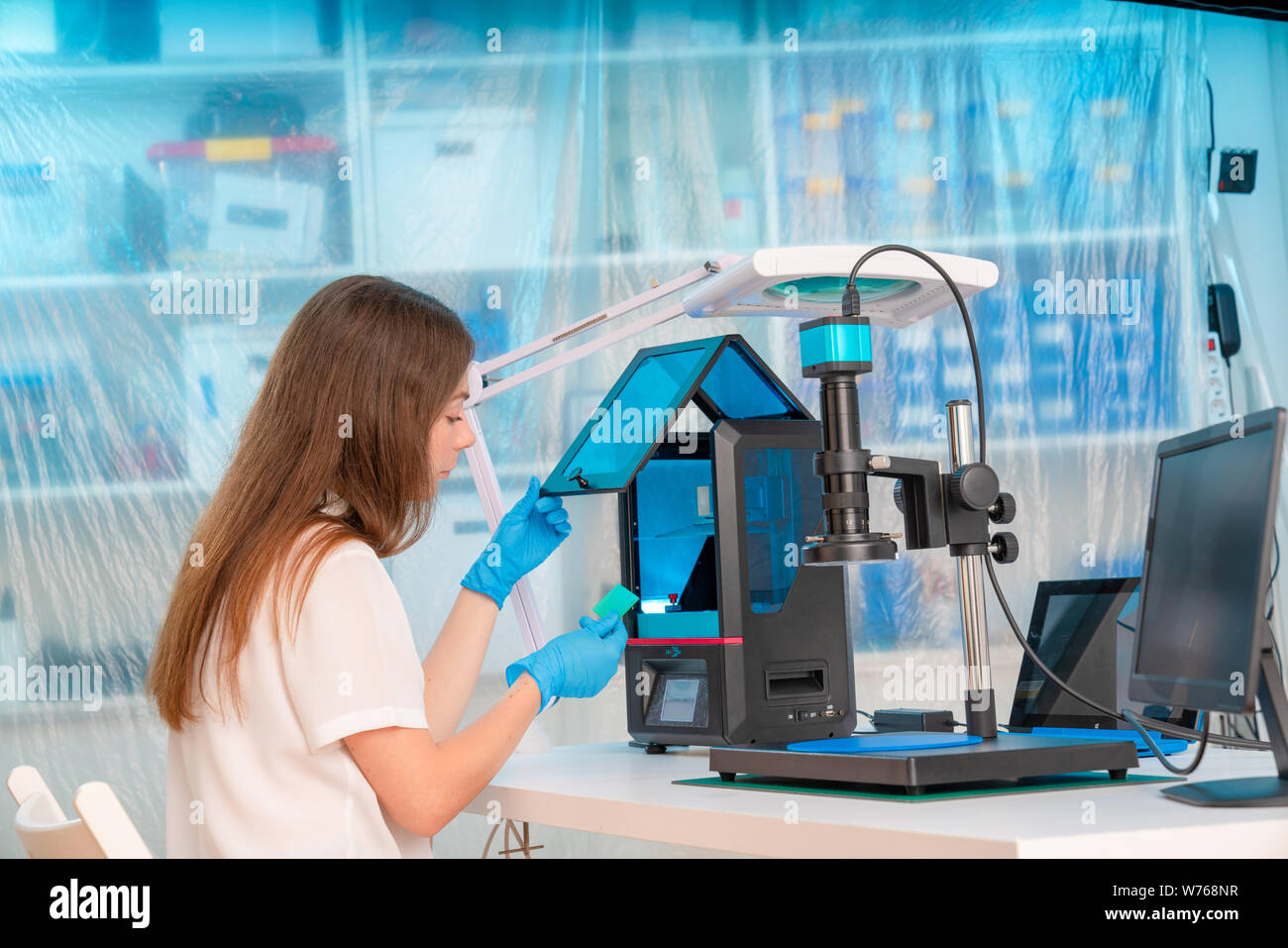 Lavoratore di sesso femminile nel controllo di resina LCD / DLP / SLA stampante 3D nel laboratorio di tecnologia Foto Stock