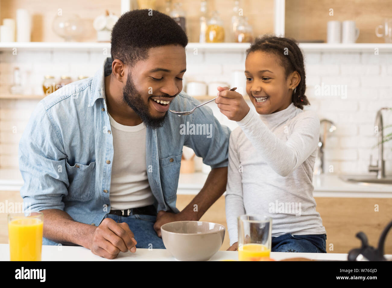 Adorabile ragazza afro alimentando il suo papà cereali Foto Stock