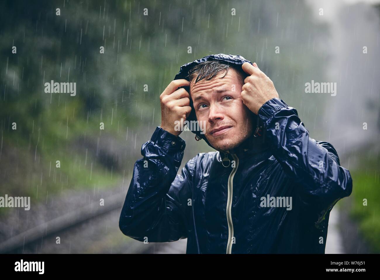 Viaggio in cattive condizioni atmosferiche. Ritratto di giovane uomo in camicia inzuppato in heavy rain. Foto Stock