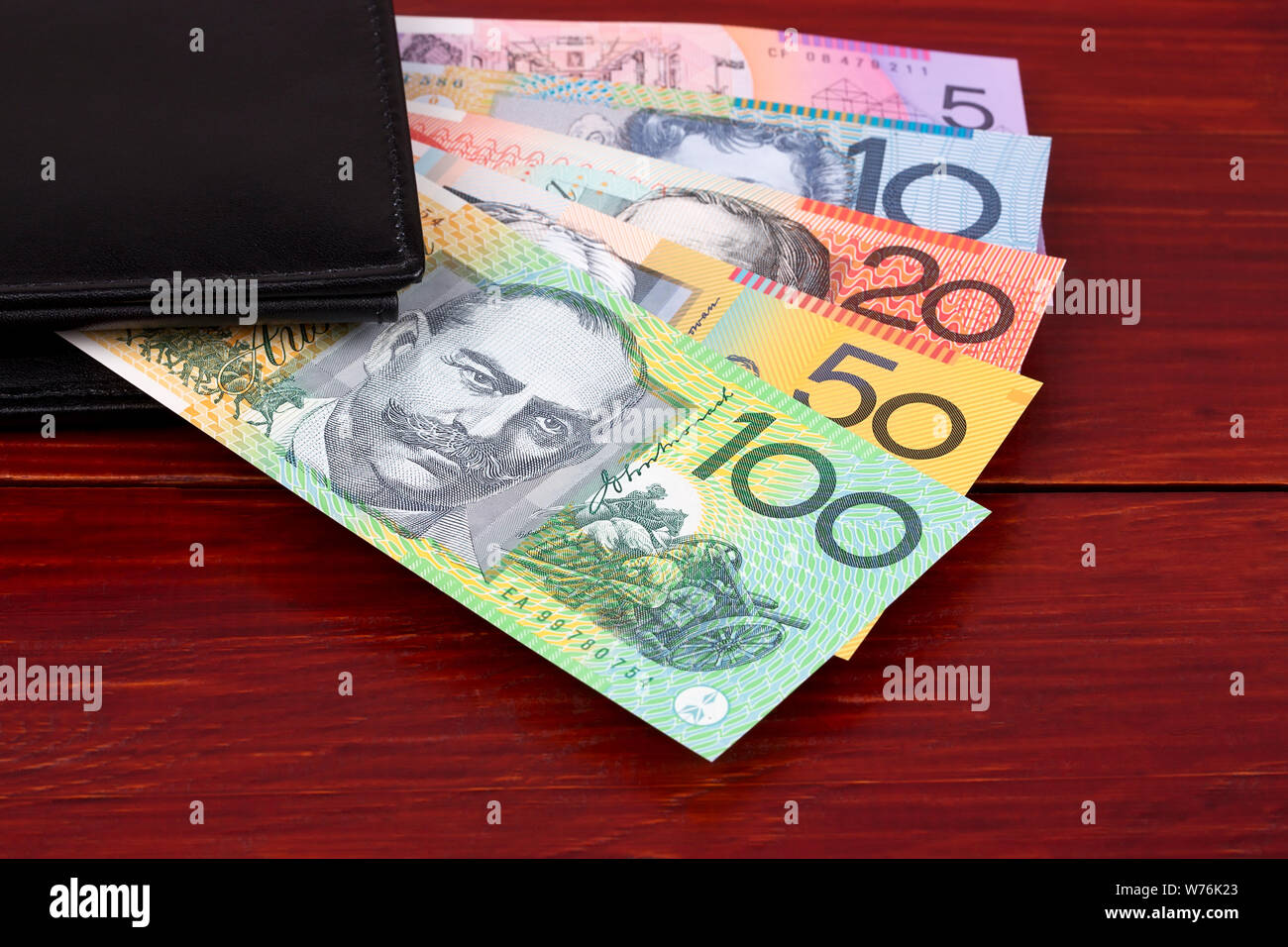 Dollari australiani nel portafoglio nero su uno sfondo di legno Foto Stock