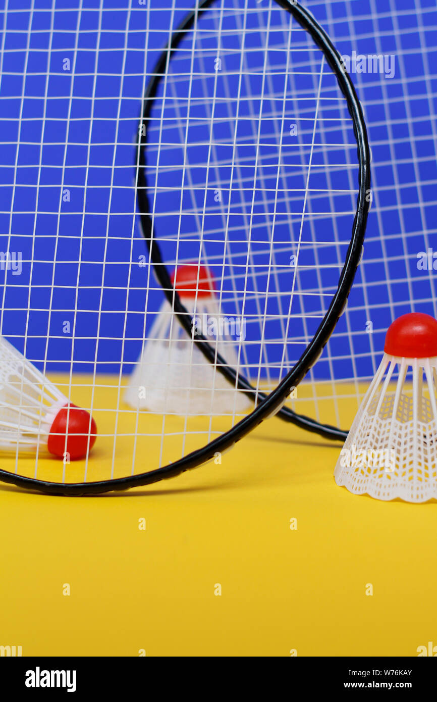Badminton. Tre volani e due badminton racchetta. Il colore di sfondo è blu e giallo. Idea per una rivista. Foto Stock