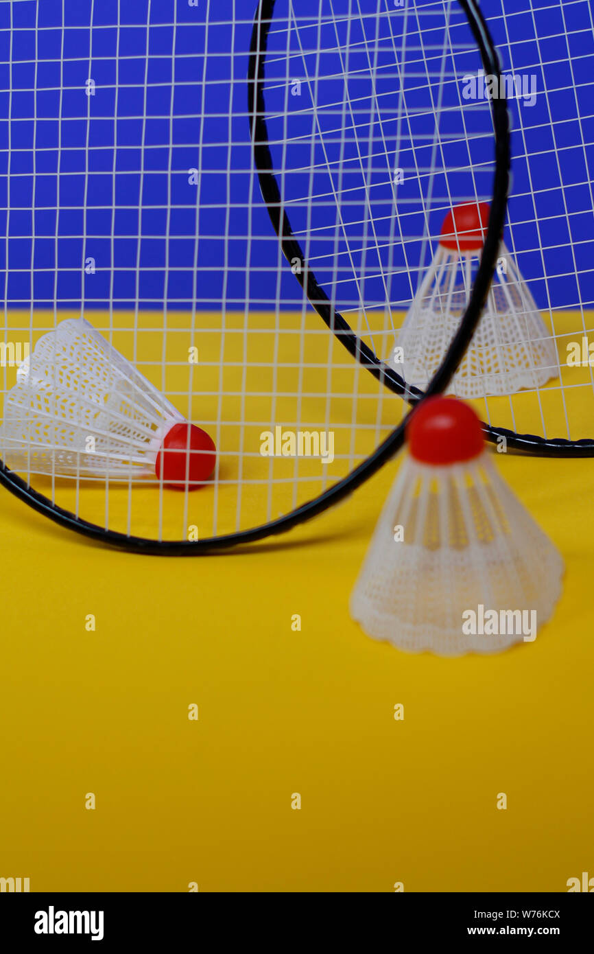 Badminton. Tre volani e due badminton racchetta. Il colore di sfondo è blu e giallo. Idea per una rivista. Foto Stock