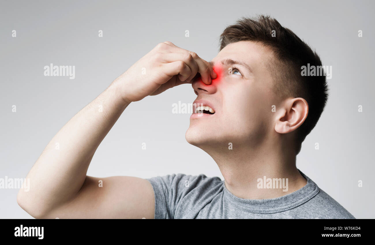 Giovane uomo di toccare il suo naso di sanguinamento, panorama Foto Stock