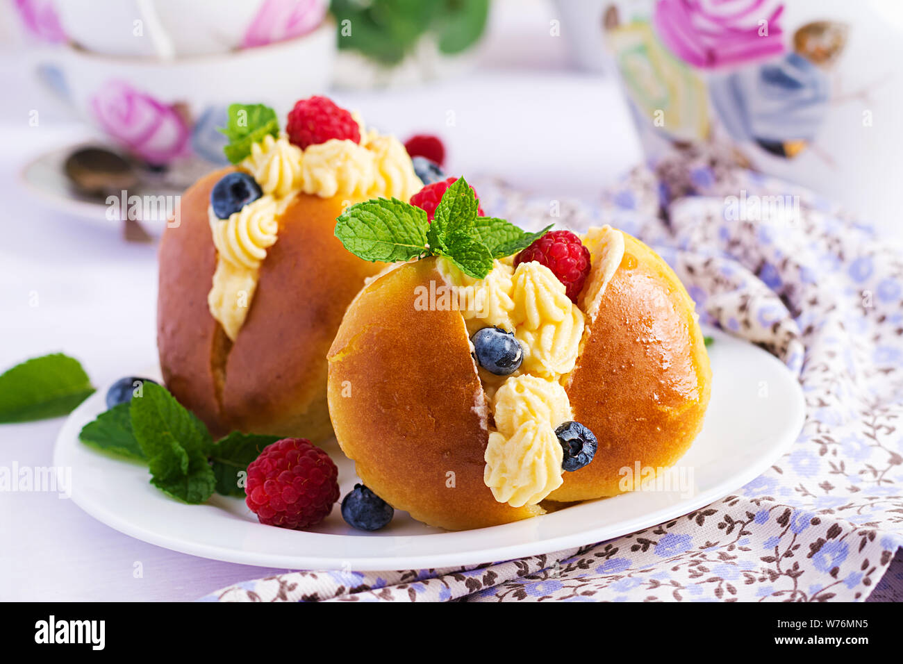 Il Rum baba decorate con panna montata e fresca lampone, mirtillo. Savarin al rum, crema e frutti di bosco. Cucina italiana Foto Stock