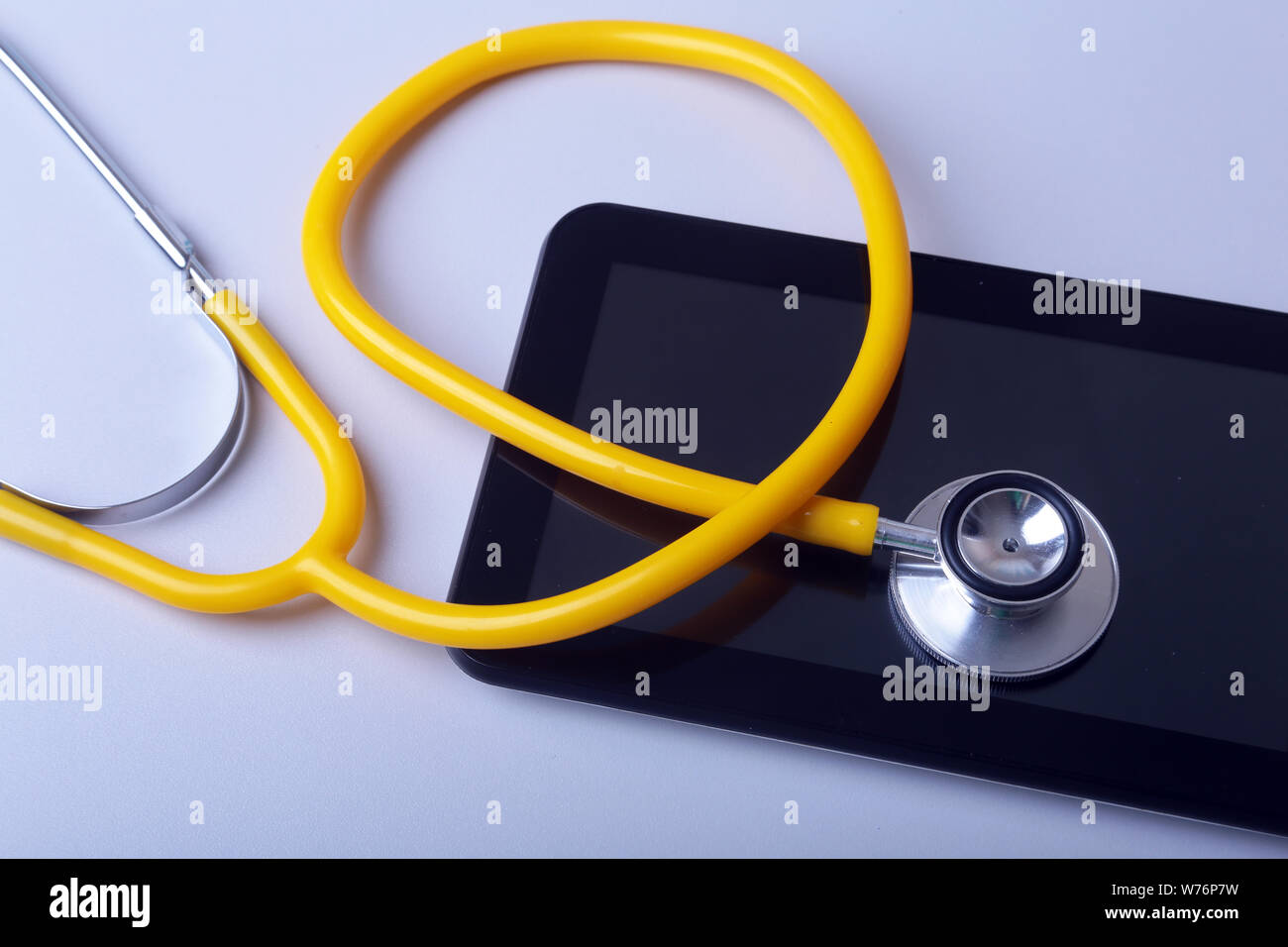 Apparecchiature mediche: stetoscopio blu e tablet su sfondo bianco. Foto Stock