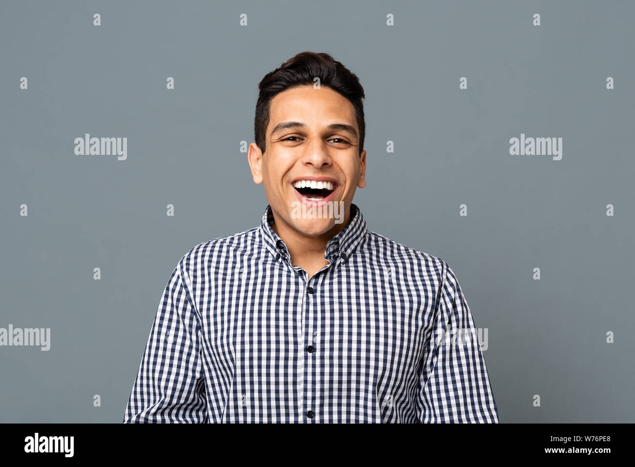 Ritratto di positivo ragazzo arabo di ridere su sfondo grigio Foto Stock