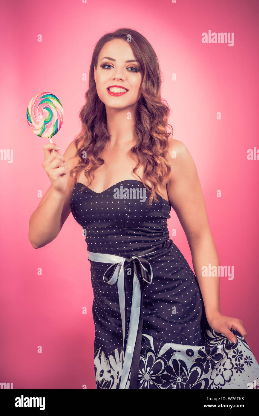 Donna con rossetto rosso detiene candy lollipop grande per la pubblicità di prodotti. Meravigliosa espressione. Foto Stock