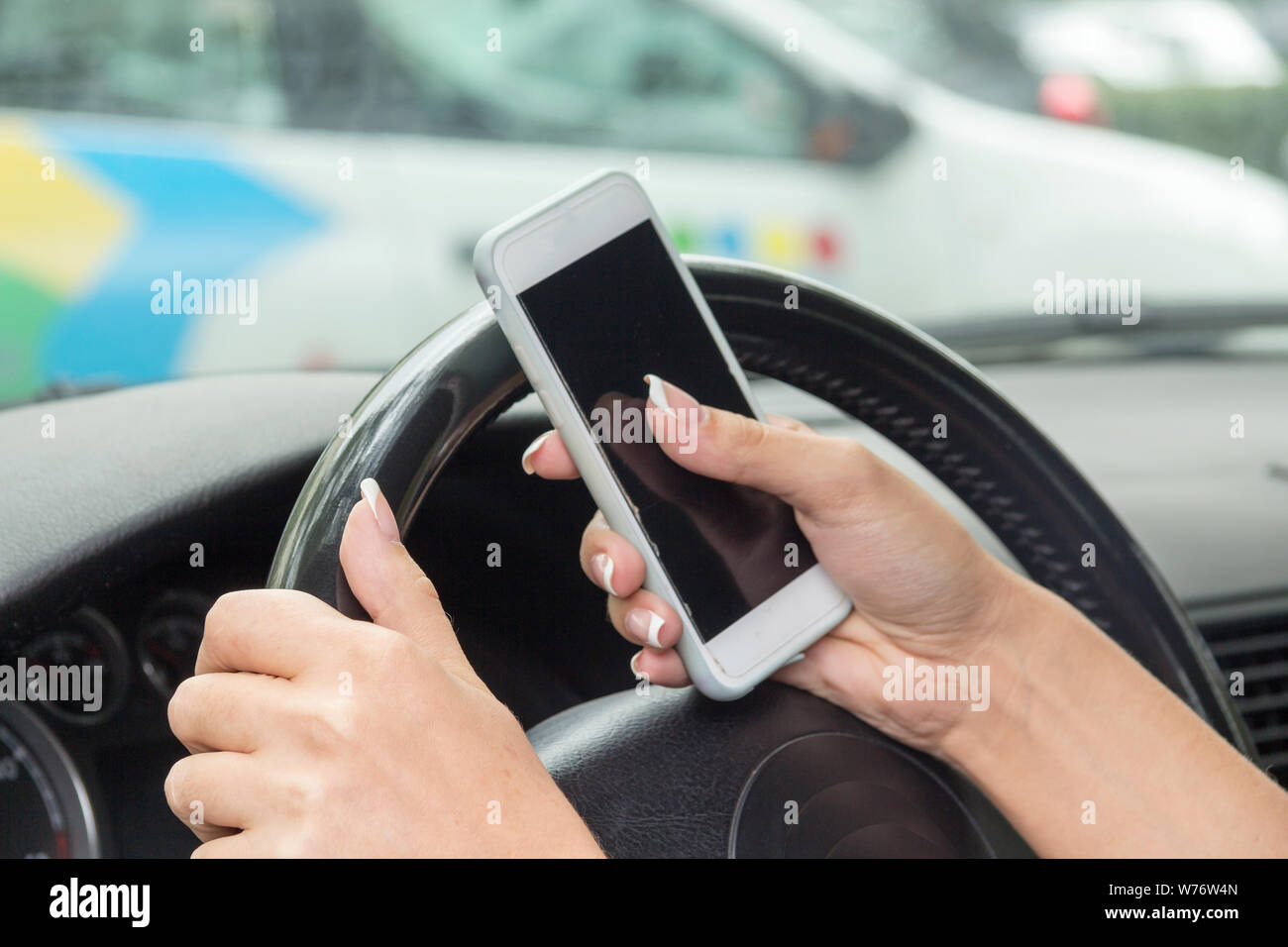 Ragazza con un telefono mobile dietro la ruota nella berlina Foto Stock