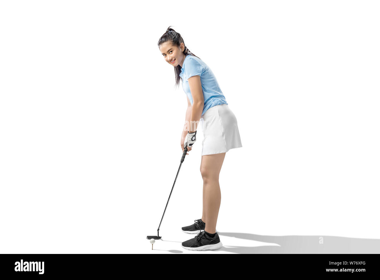 Donna asiatica con un putter golf club pronti a colpire la palla isolate su sfondo bianco Foto Stock