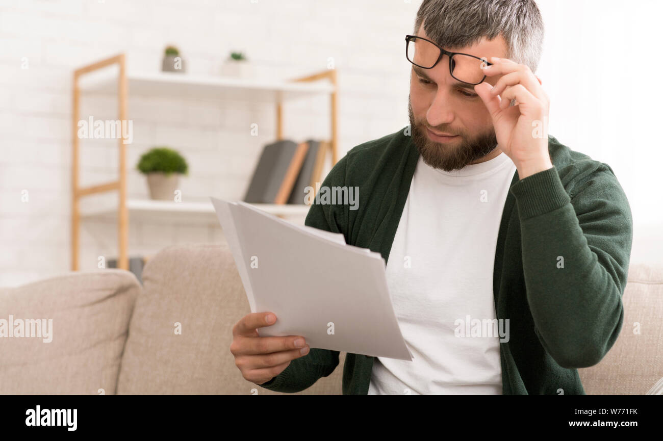 Di mezza età uomo caucasico la lettura di carte a casa Foto Stock
