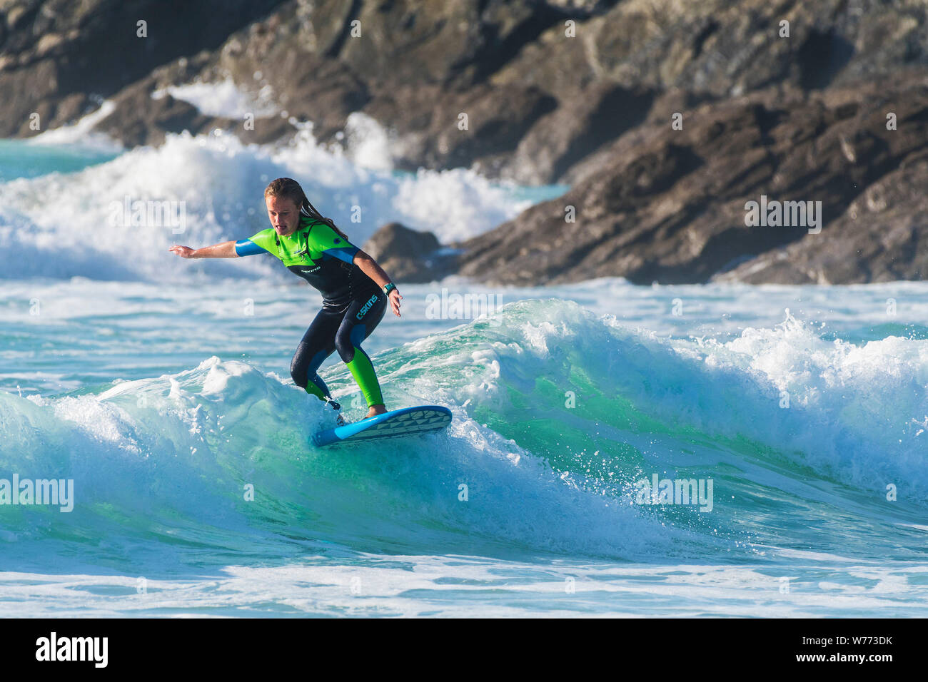 Un surfista femmina a cavallo di un onda al Fistral a Newquay in Cornovaglia. Foto Stock