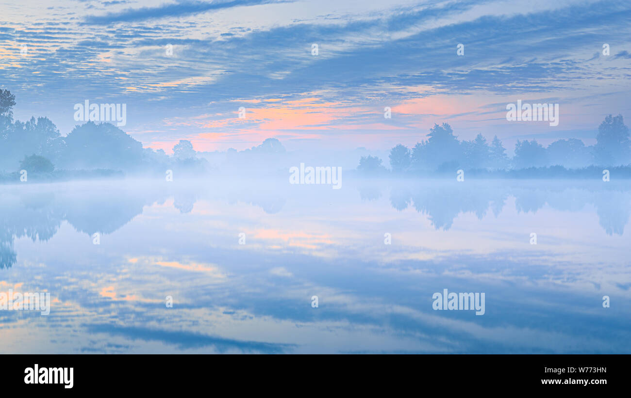 Una splendida e tranquilla posizione idilliaca tramonto su un lago con colori blu e un riflesso in acqua - Paesi Bassi Foto Stock