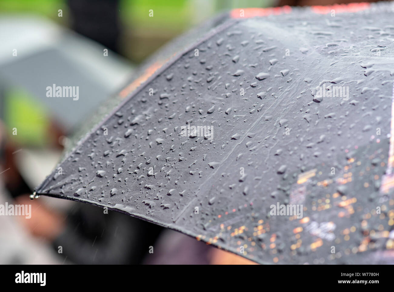 Giorno di pioggia, Heavy Rain in città, gocce sulla superficie di Ombrello nero, persone con ombrelloni durante la tempesta Foto Stock