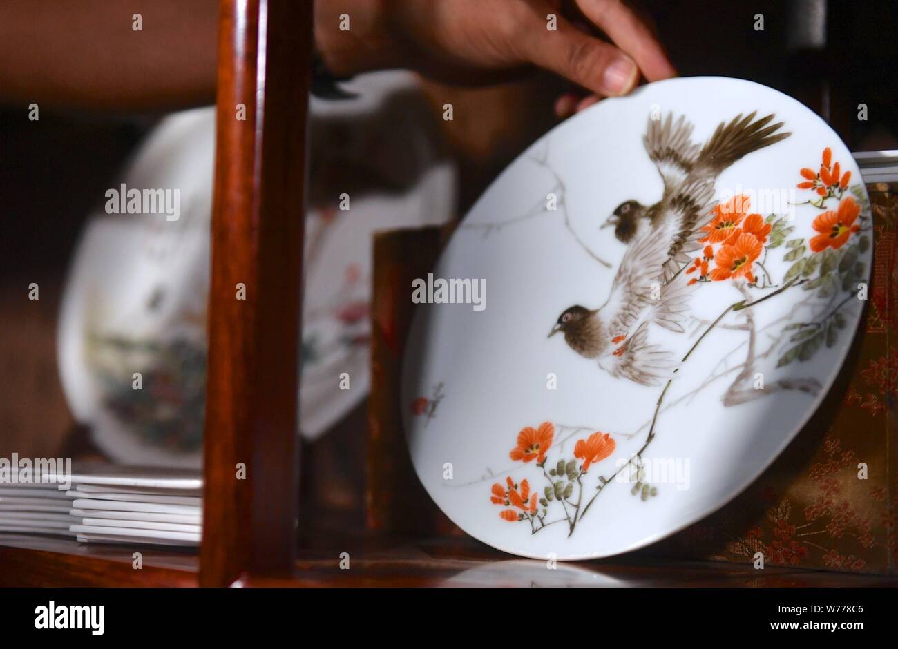 (190805) -- NANCHANG, e il Agosto 5, 2019 (Xinhua) -- Mao Guanghui pone un pezzo di porcellana dipinto sul ripiano nel suo studio di Jingdezhen, Cina orientale della provincia di Jiangxi, e il Agosto 1, 2019. Mao Guanghui, un 56-anno-vecchio maestro senior di arti e mestieri nella provincia di Jiangxi, si dedica alla pittura su porcellana fin dall'età di 13. Come una terza generazione di discepolo di Deng Bishan (1874-1930), una delle 'Otto Amici di Zhushan', un gruppo di artigiani di Jingdezhen ampiamente noti per le loro innovazioni in porcellana dipinto, Mao ha ereditato non solo la capacità ma anche la tecnica di creazione di vernice di porcellana Foto Stock