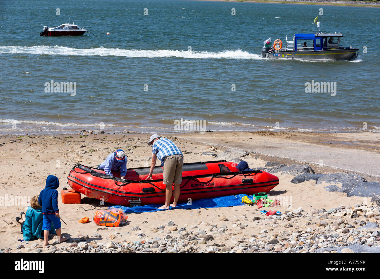 Una famiglia preparare un gommone su una spiaggia di Ferryside, Carmarthenshire Foto Stock