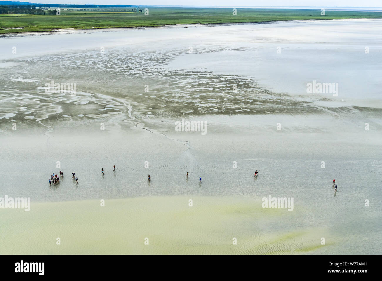 Antenna ampio paesaggio di St Michel bay a bassa marea con un gruppo di persone escursionismo, costa della Normandia, Francia. Foto Stock