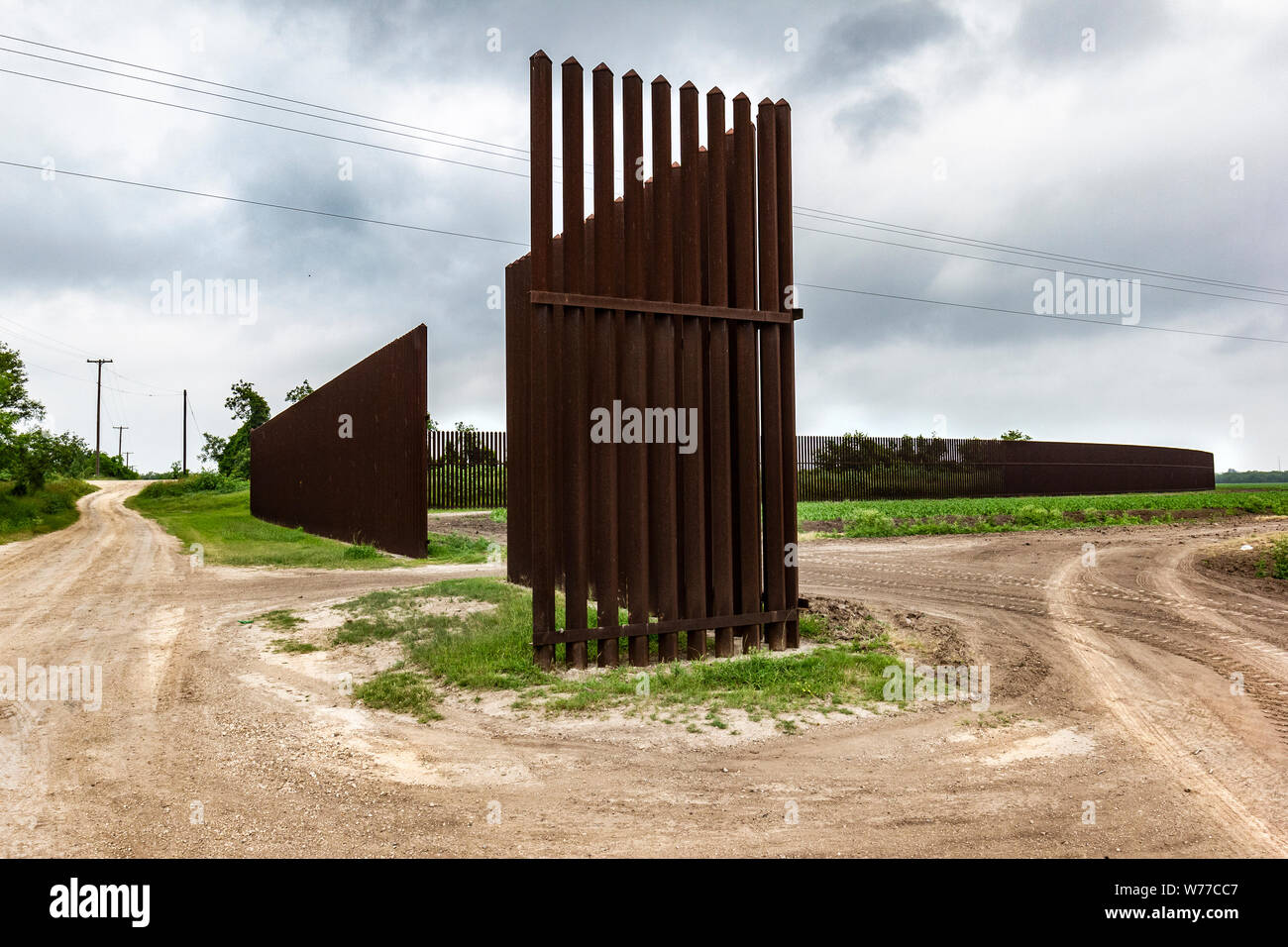 Giovani stocchi di mais crescono in un campo nei pressi di una sezione di la recinzione di confine in Los Indios non lontano dal ponte internazionale di Los Indios, TX, Stati Uniti d'America. Molto spesso farmerland è suddivisa con i campi su entrambi i lati del confine. Foto Stock