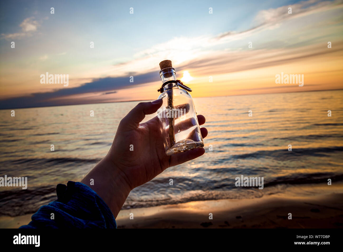 Messaggio in bottiglia contro il sole che tramonta verso il basso Foto Stock