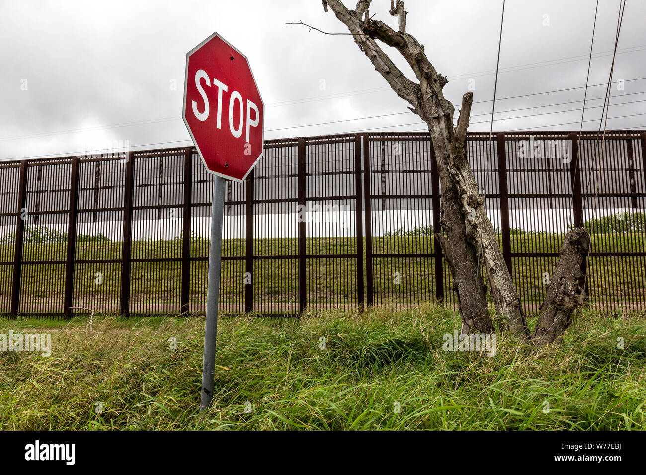 Il segnale di arresto di fronte al muro di confine con il Messico, Brownsville, Texas, Stati Uniti d'America Foto Stock