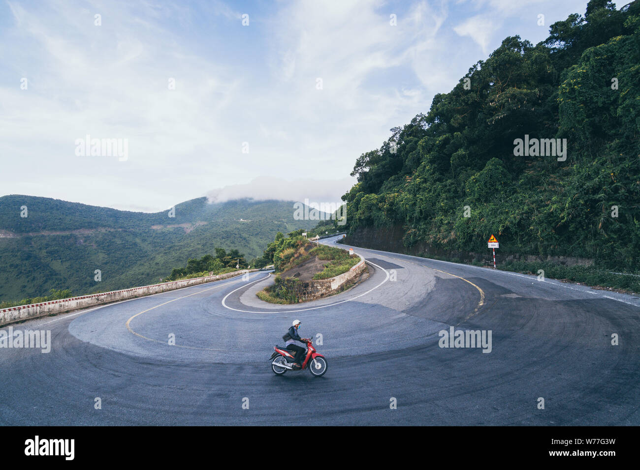 Uomo rosso di equitazione motocicletta su strade tortuose di Hai Van pass da Hue città di Hoi An, Vietnam Foto Stock