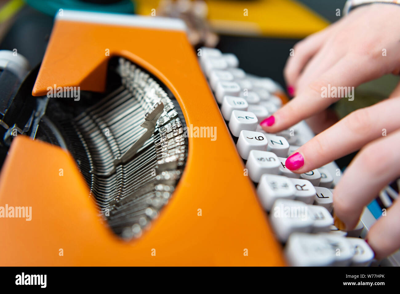 Le donne le dita con le unghie rosa tipo sulla macchina da scrivere di colore arancione. Foto Stock