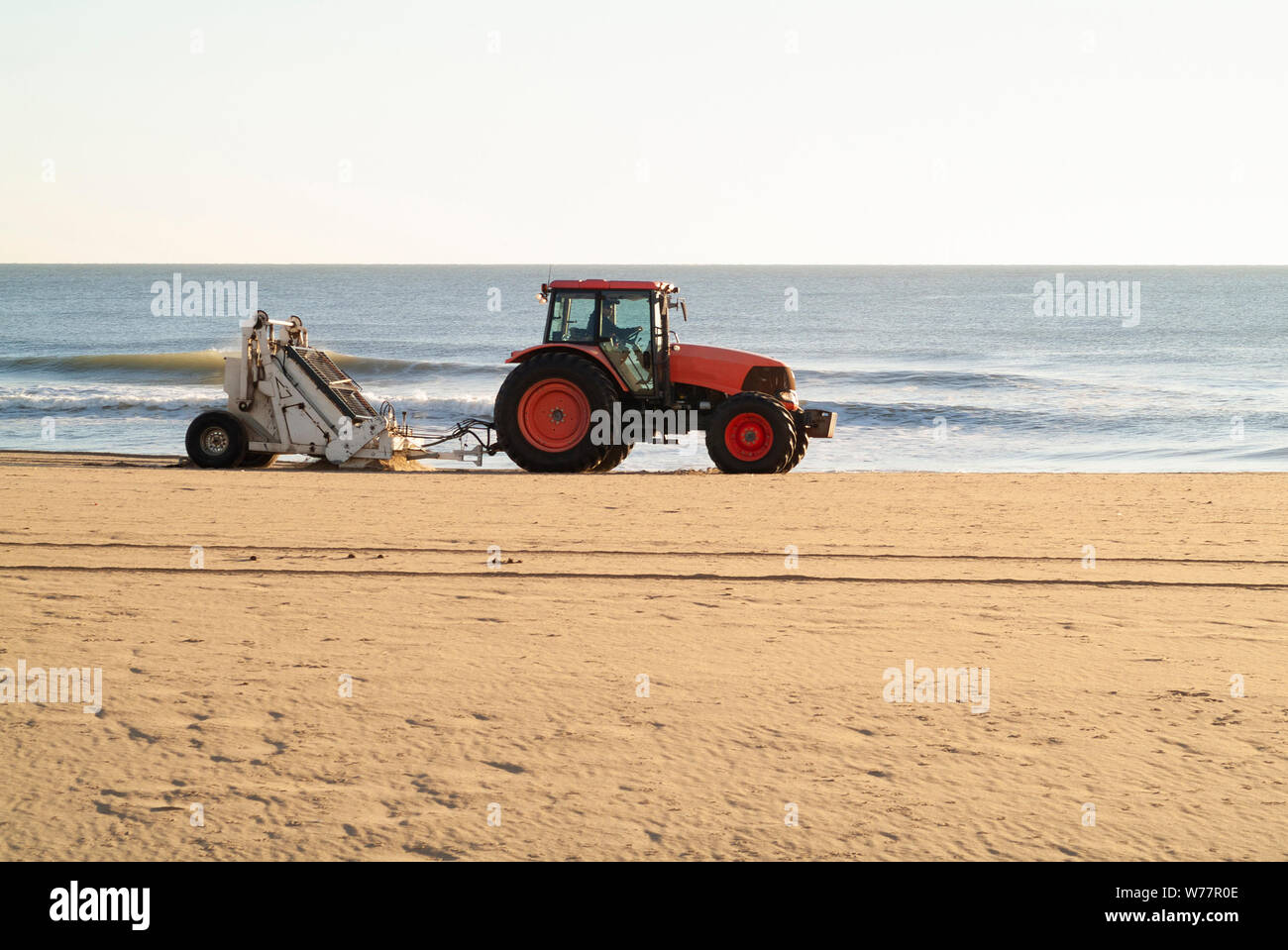 SPAZZATA mattutina: Un trattore con un dispositivo di vagliatura collegato pulisce e rimuove i rifiuti dalla spiaggia della Virginia nelle prime ore dell'alba. Foto Stock