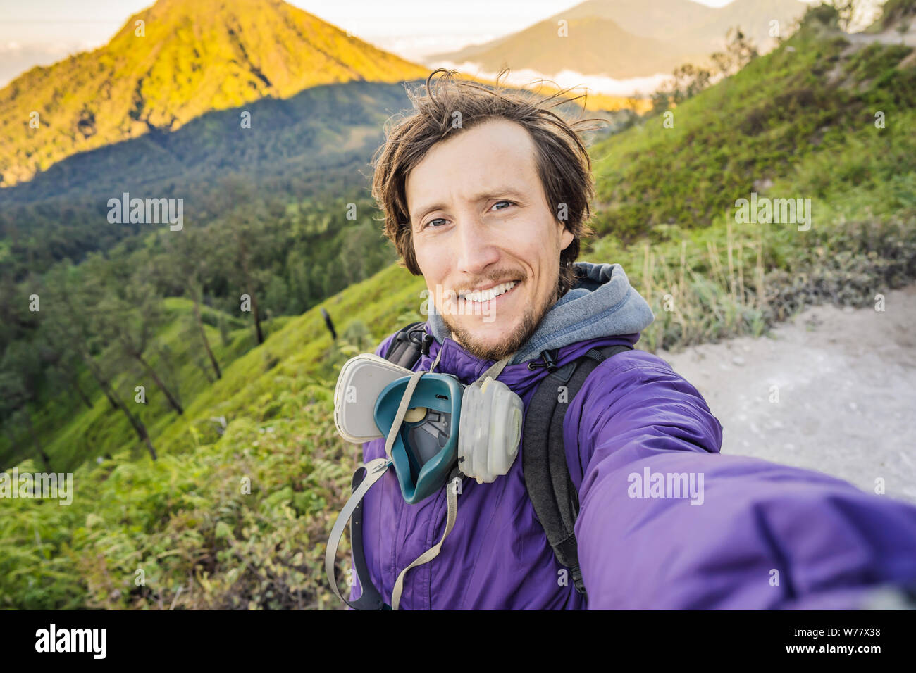 Giovane turista fa un selfie con magnifiche vedute sulle montagne verdi da una strada di montagna bici al vulcano Ijen o Kawah Ijen sul Foto Stock