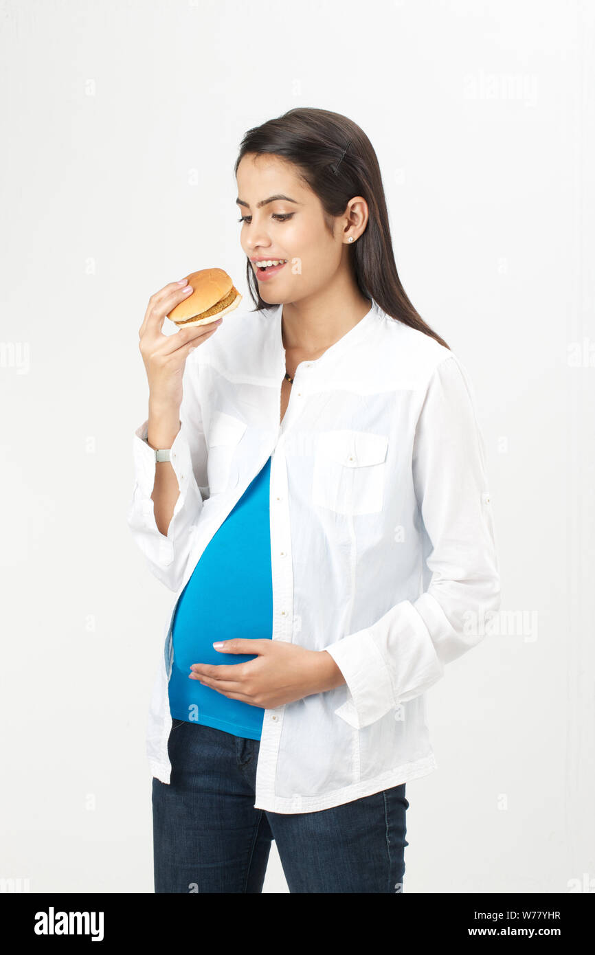 Donna incinta di mangiare hamburger Foto Stock