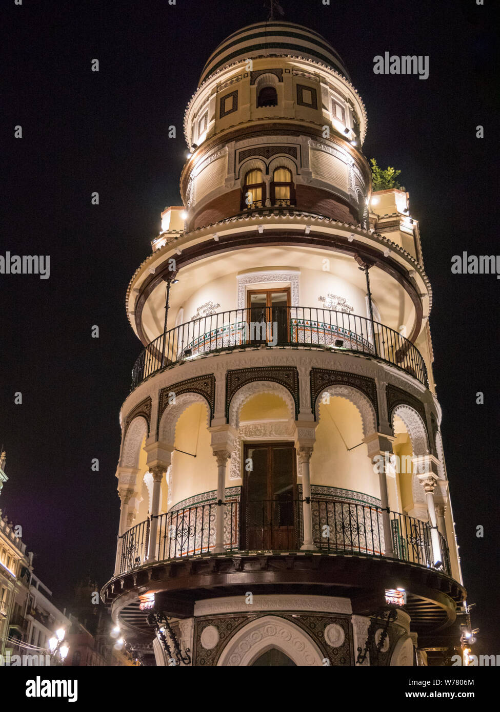 Un tradizionale edificio ornato e blocco di appartamenti nella parte vecchia di Siviglia Spagna notturna illuminata da luci di strada e di illuminazione interna Foto Stock