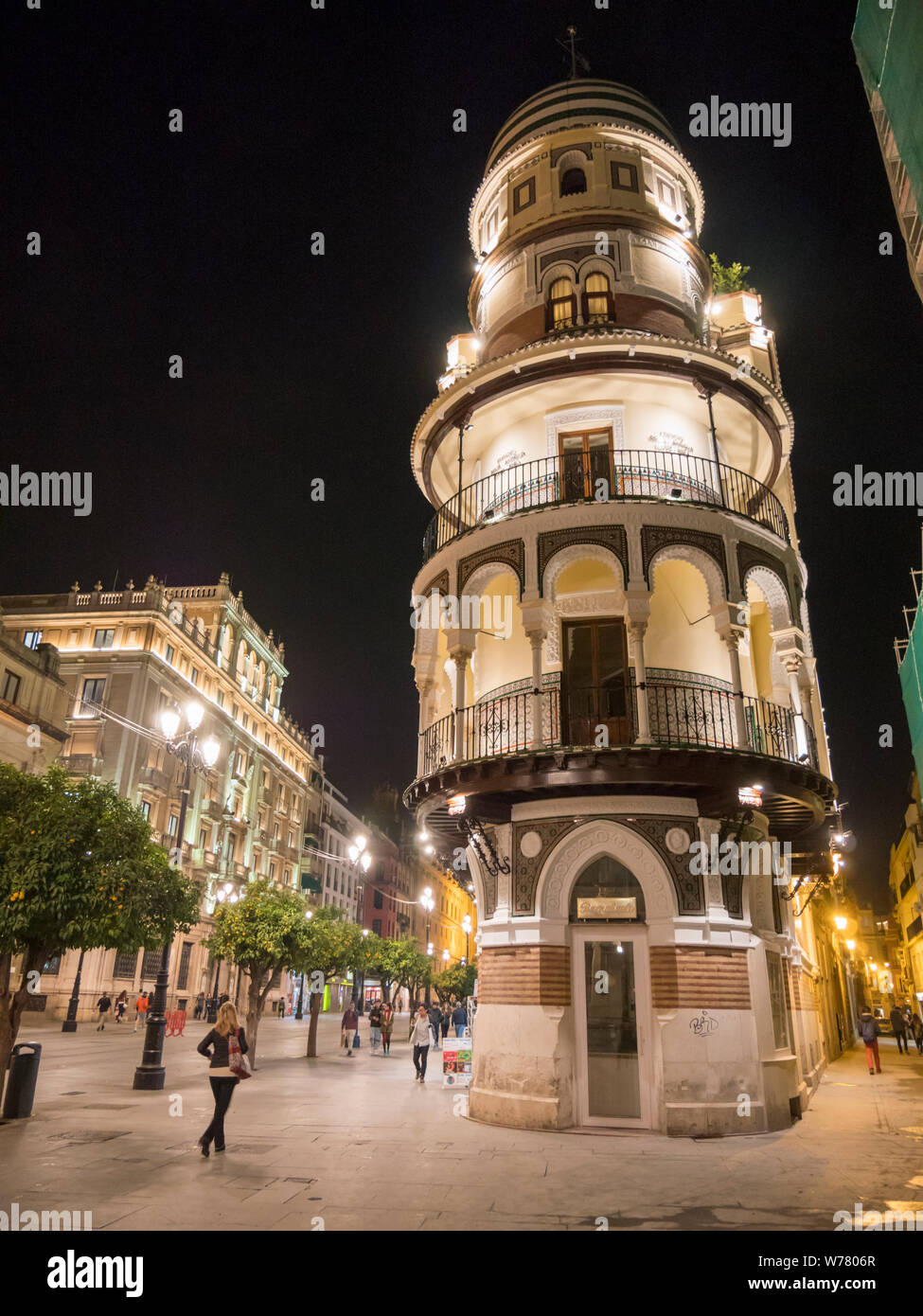 Un tradizionale edificio ornato e blocco di appartamenti nella parte vecchia di Siviglia Spagna notturna illuminata da luci di strada e di illuminazione interna Foto Stock
