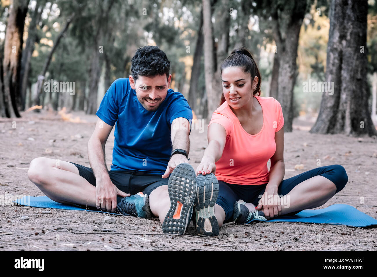 Giovane seduto in un parco a fare esercizi di stretching Foto Stock