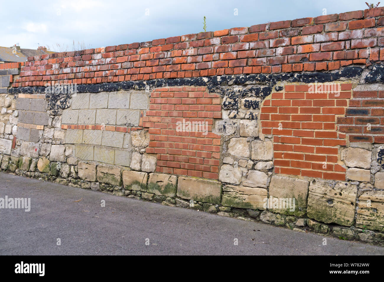 Un muro di mattoni in una città che è stata riparata molte volte Foto Stock