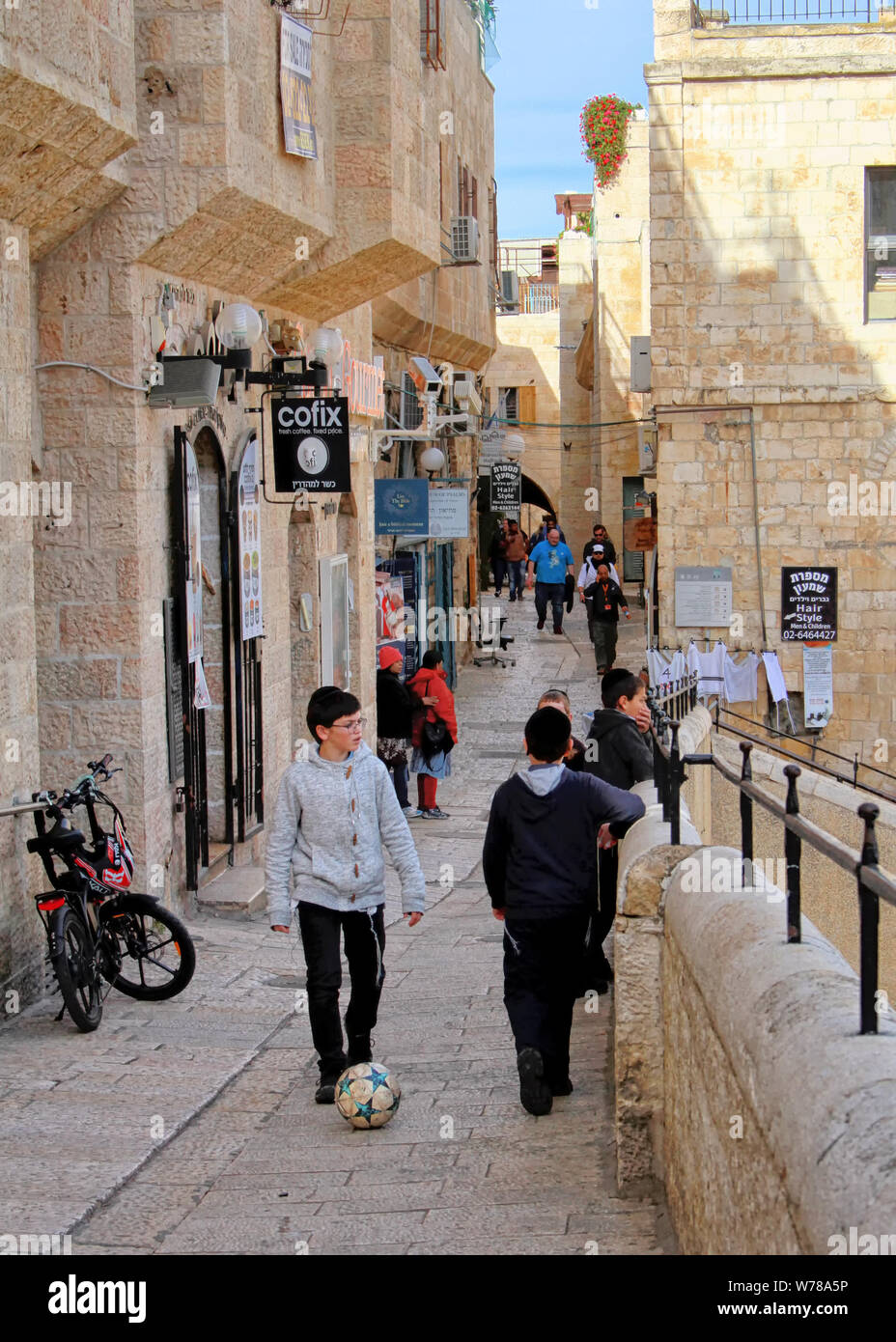 Ragazzi dare un calcio a un pallone da calcio in fondo a una strada nel quartiere ebraico di Gerusalemme la città vecchia, vicino il cardo romano. Foto Stock