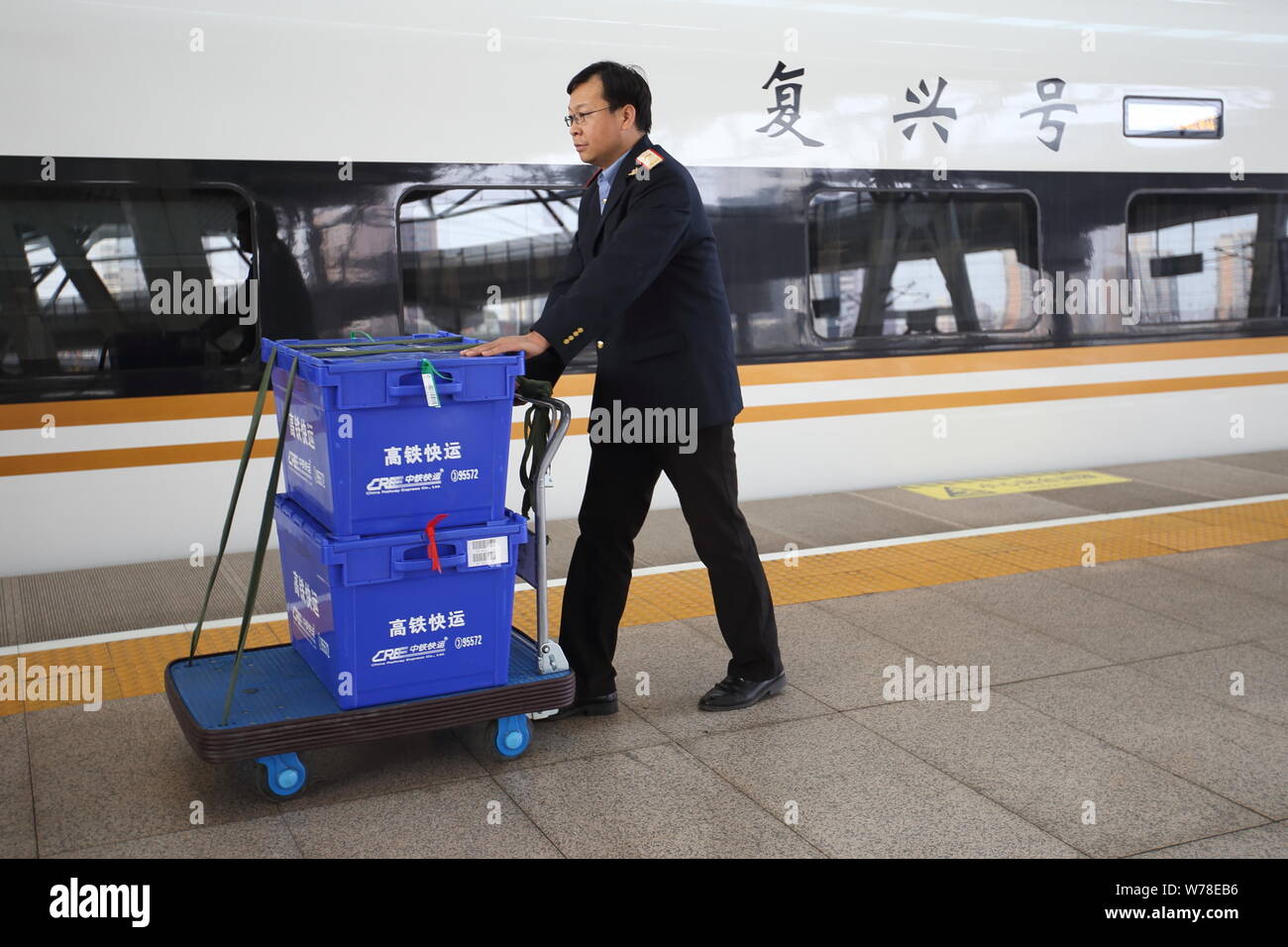 Un dipendente cinese di CRE (China Railway Express) sposta le scatole con i pacchi all'interno lungo un 'Fuxing' bullet train in esecuzione sul Beijing-Shanghai hi Foto Stock