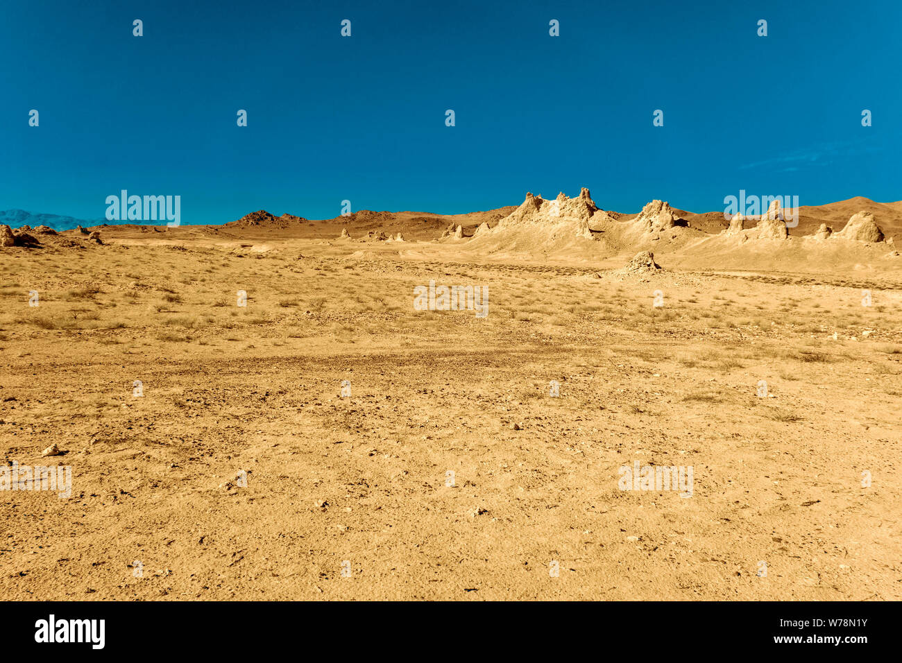 Luce marrone giallo deserto piano valley con formazioni rocciose sotto cieli azzurri. Foto Stock