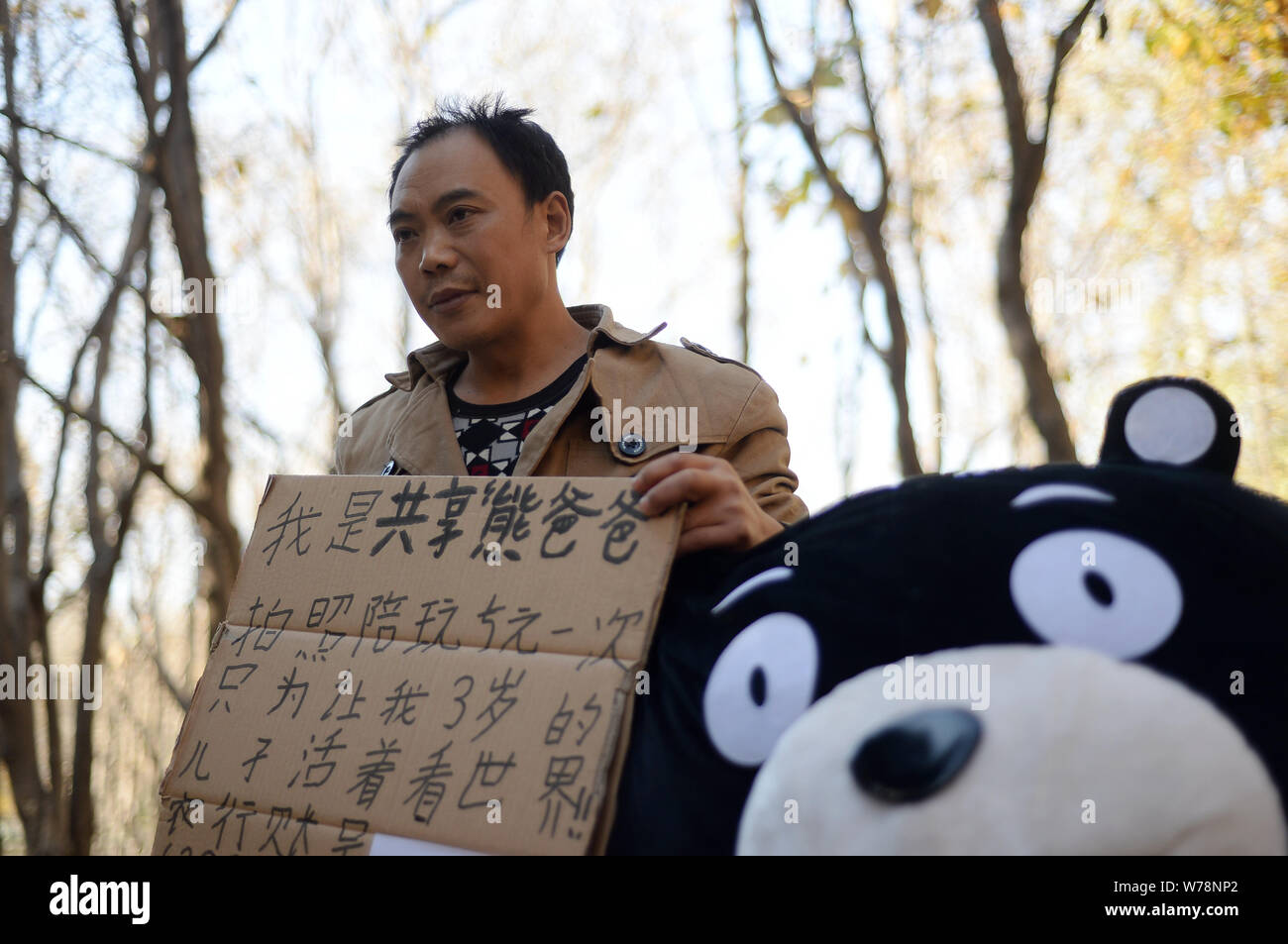 Il 45-anno-vecchio uomo cinese Cao Licai abiti fino come il Giappone Kumamon mascotte di posa per le foto con i residenti locali per raccogliere fondi per il suo 3-anno-vecchio figlio d Foto Stock