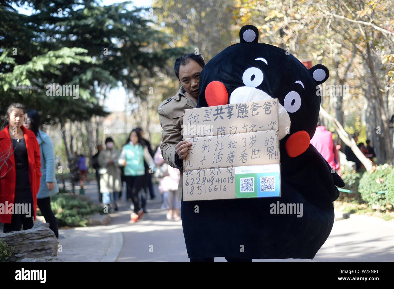 Il 45-anno-vecchio uomo cinese Cao Licai abiti fino come il Giappone Kumamon mascotte di posa per le foto con i residenti locali per raccogliere fondi per il suo 3-anno-vecchio figlio d Foto Stock
