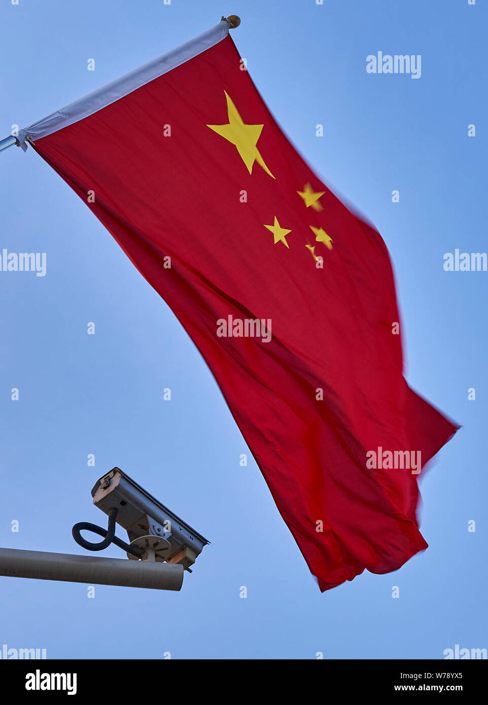 Una bandiera cinese sventolare nel vento e una videocamera di sorveglianza sotto la bandiera. La foto è stata scattata a Piazza Tiananmen, Pechino. Foto Stock
