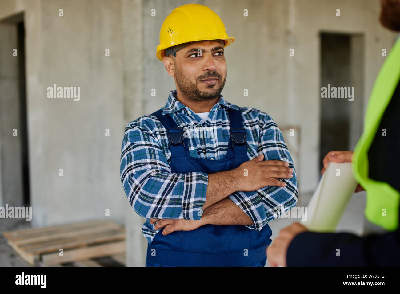 Due ingegneri discutere il lavoro domande collegate insieme tenendo ripiegati blueprint. Foto Stock