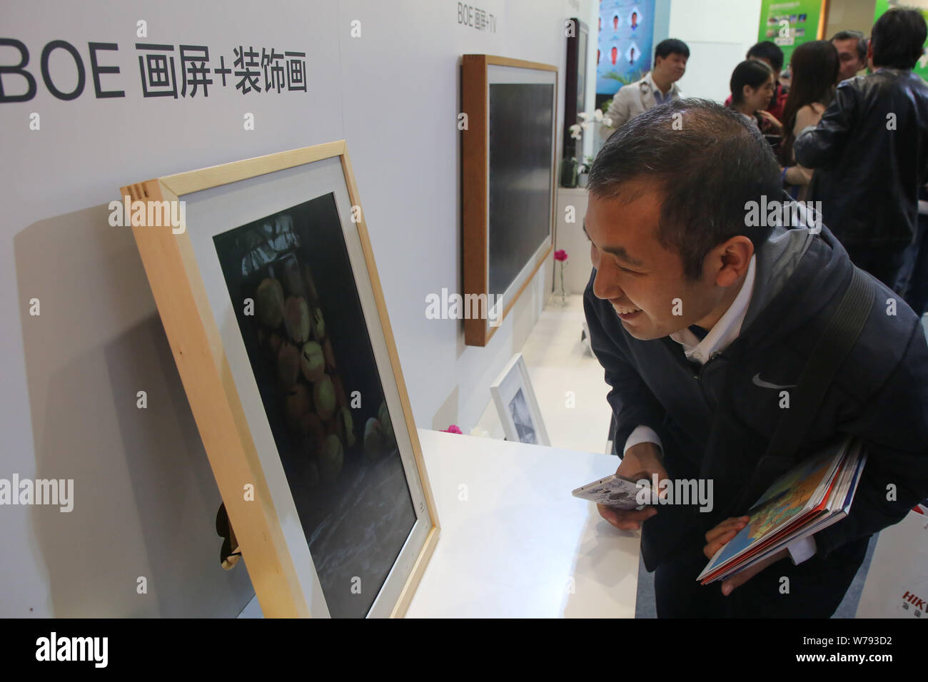 Un visitatore guarda una cornice fotografica digitale di BOE Technology Group sul display durante il XIV Optics Valle del China International Exposi optoelettronici Foto Stock