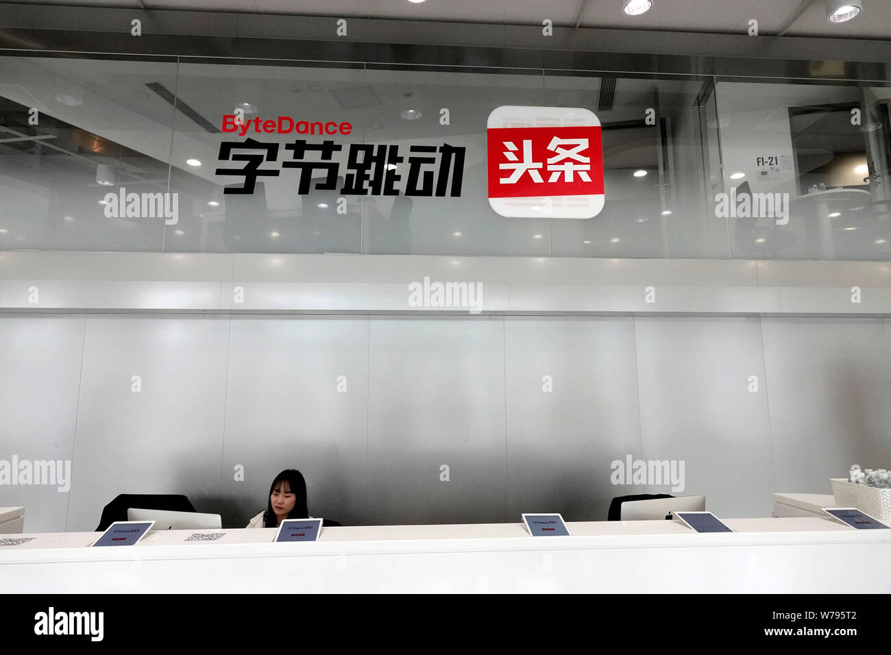 Un dipendente cinese è visto presso il banco della reception in sede cinese di notizie personalizzate app Toutiao.com di Bytedance Ltd. a Pechino, Cina Foto Stock