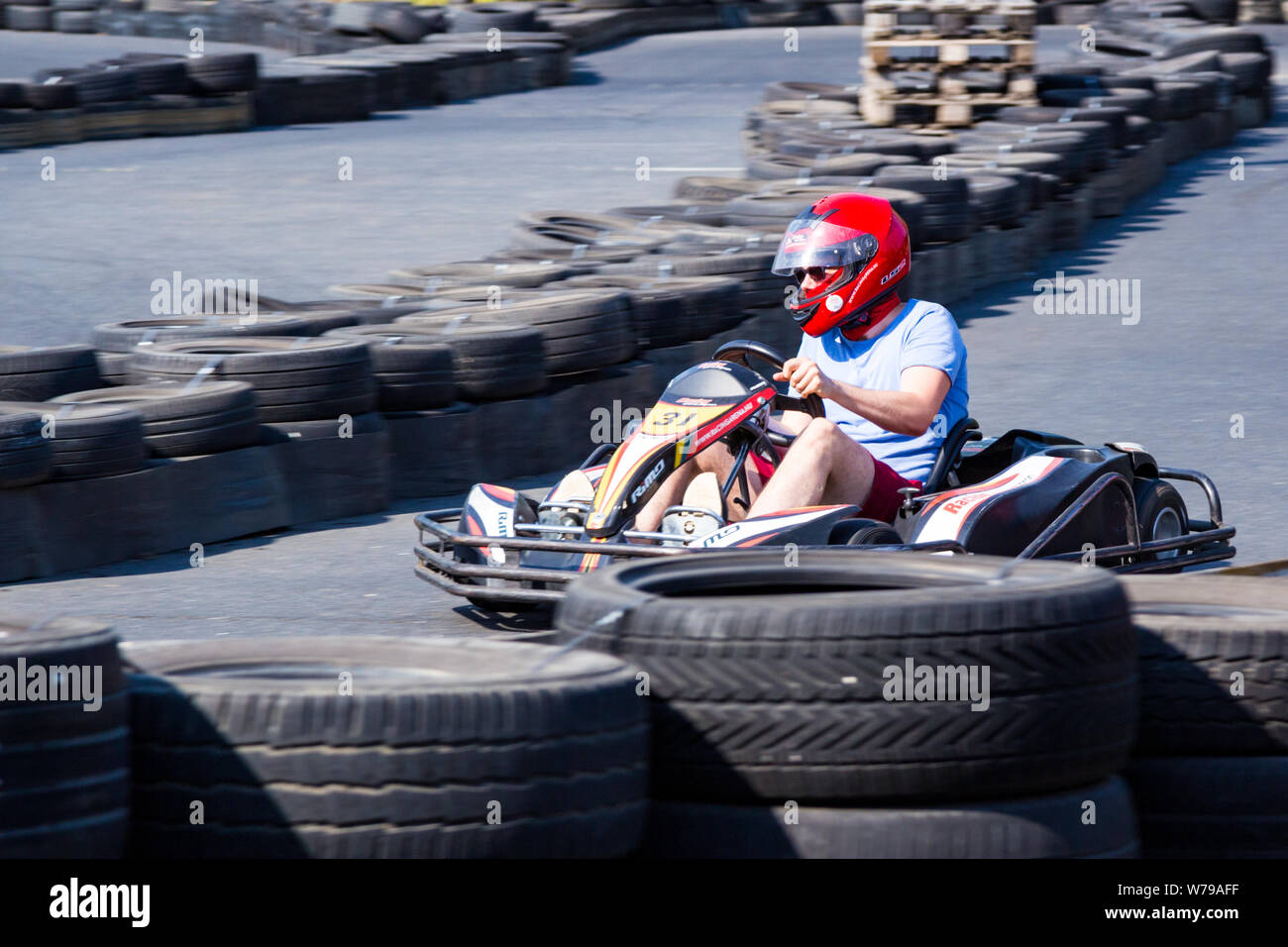 Go-kart in rosso casco tenendo la piega tra sicurezza barriere di pneumatici Foto Stock